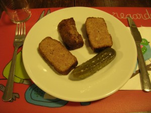 slices of meat loaf in a dish with a dill pickle